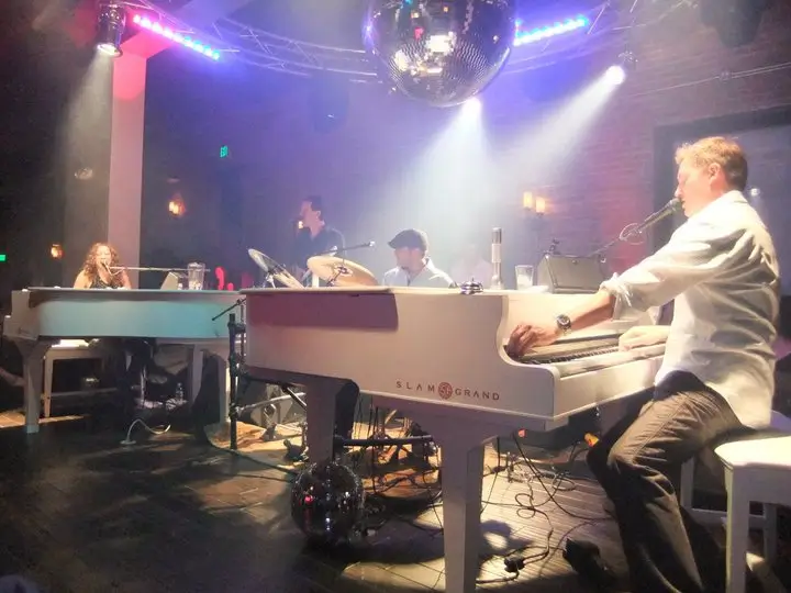 A group of people sitting around a piano.